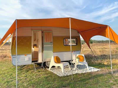 oranje caravanity trekking luifel met stoelen en vintage caravan